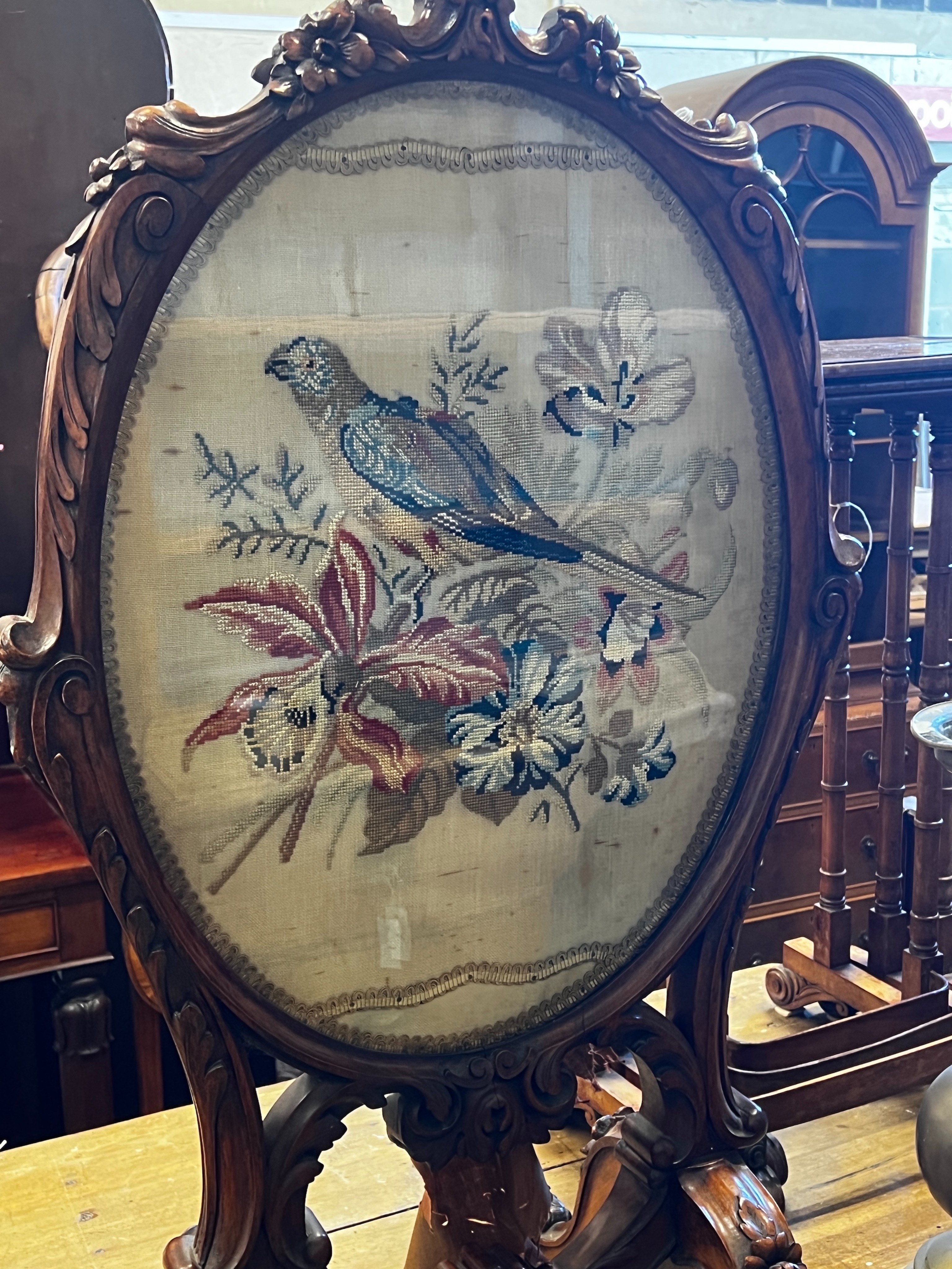 A Victorian carved walnut fire screen with needlework parrot banner, width 56cm, height 99cm